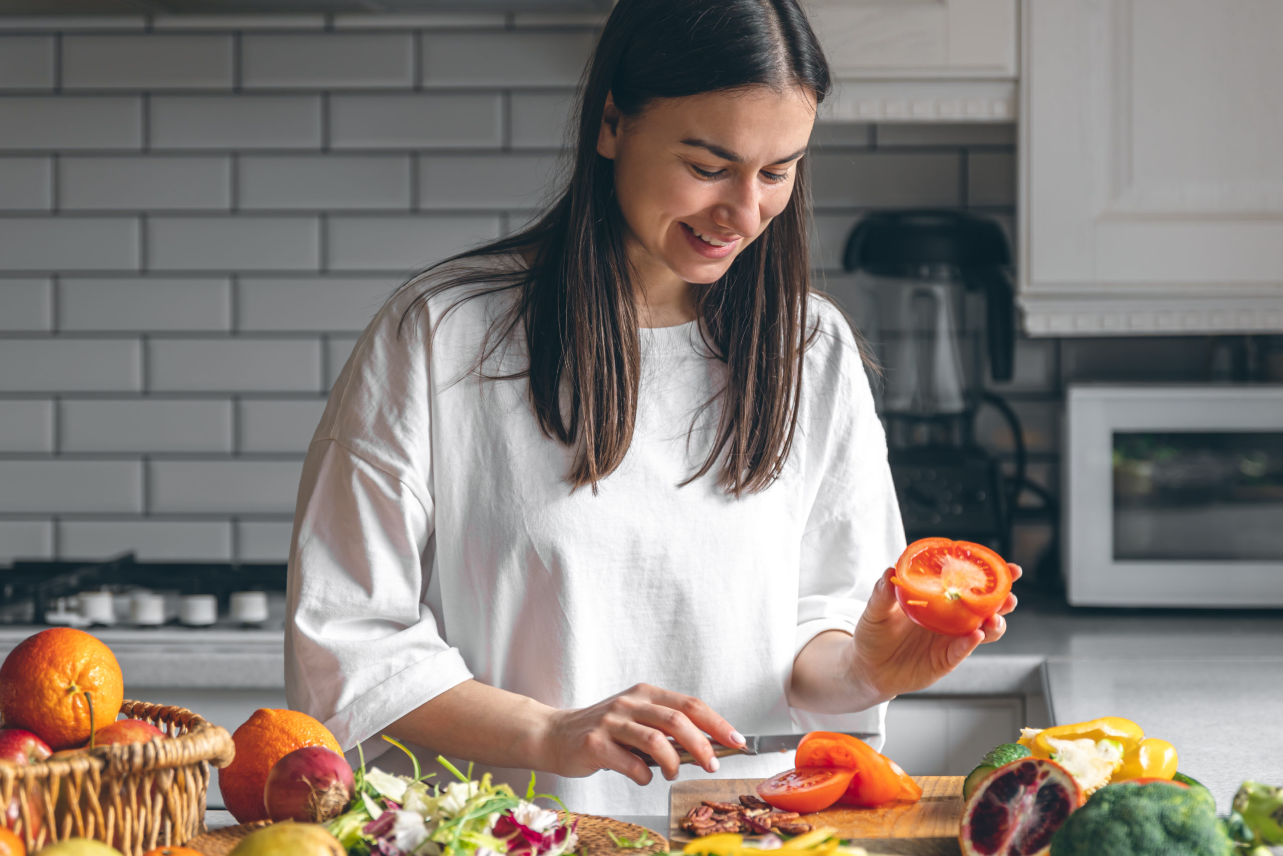 Jeune femme coupant des légumes sur un plan de travail, dans une cuisine. Vous pouvez vous aussi cuisiner en étant malvoyant !